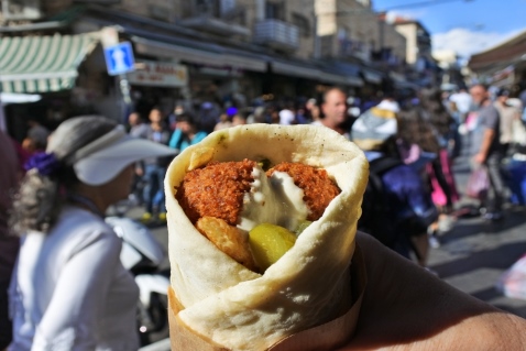 photo of falafel pita wrap in Jerusalem market with crowded street in the background
